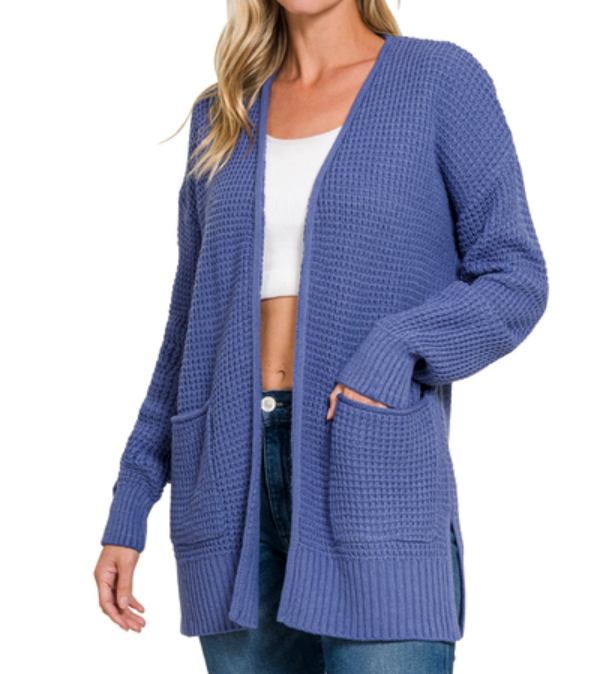 Woman wearing a blue cardigan over a white top and jeans on a white background